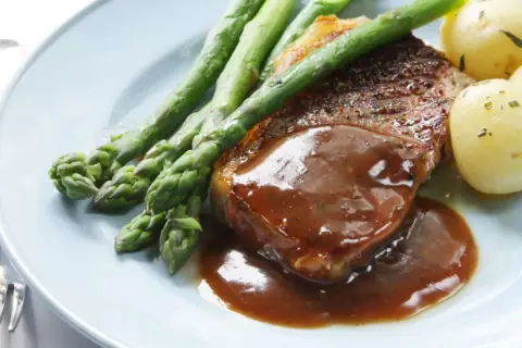 Un délicieux steak servi avec une sauce onctueuse, des asperges croquantes et des pommes de terre nouvelles. Un plat parfait pour un dîner savoureux.