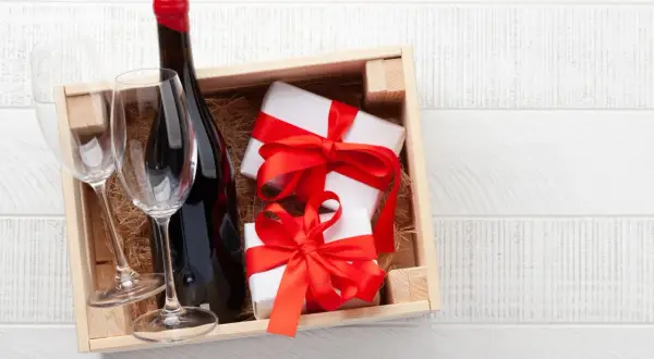 Cadeau gourmand : une bouteille de vin rouge, deux verres et des présents emballés, prêts à être dégustés dans un domaine de Bourgogne.