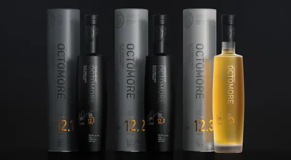 Trois bouteilles d'Octomore, whisky tourbé d'Islay, avec leurs tubes. L'une est dorée, les deux autres noires. Les étiquettes affichent des niveaux de PPM élevés, comme 130.8 PPM.