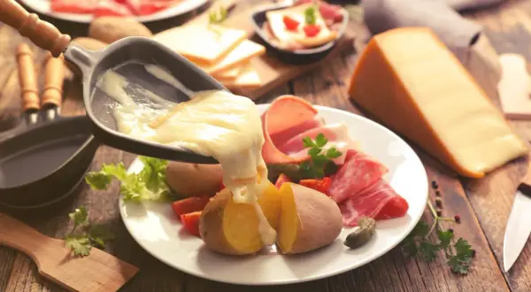 Raclette, le meilleur plat français, avec pommes de terre, charcuterie et fromage fondu. Un délice réconfortant.