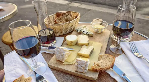 Un plateau de fromages variés, du pain et du vin rouge, une scène qui raconte une belle histoire de la cuisine française.