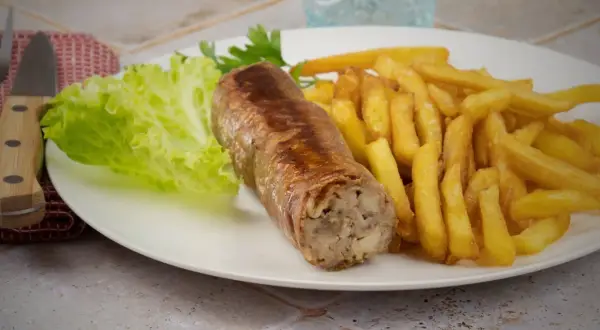 Une belle andouillette grillée avec des frites croustillantes et une feuille de laitue fraîche. Un plat simple et savoureux.