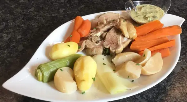 Plat de tête de veau, carottes, pommes de terre et poireaux, servi avec une sauce tartare. Une recette traditionnelle pour un repas réconfortant.