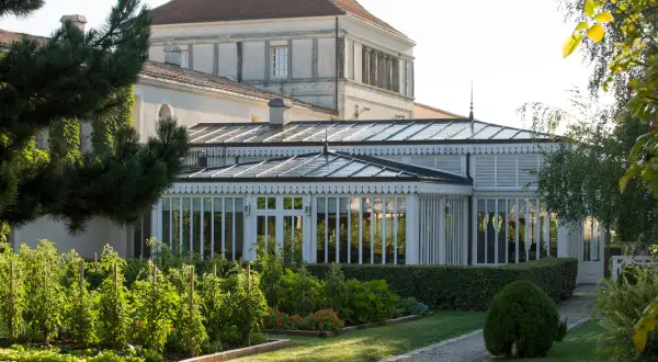Jardin luxuriant devant une serre élégante, rappelant la beauté du caudalie vignoble.