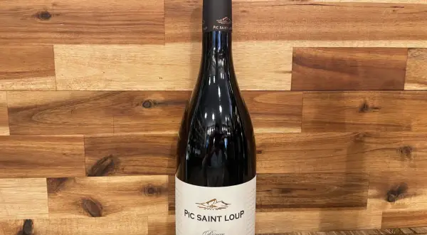 Bouteille de vin rouge du domaine Pic Saint Loup, "Réserve Les Almadies", sur fond de bois.