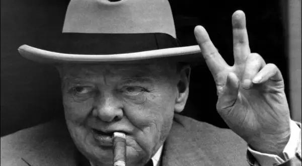 Winston Churchill, chapeau, cigare et signe de victoire. L'alcool et le cigare font partie de son image iconique.