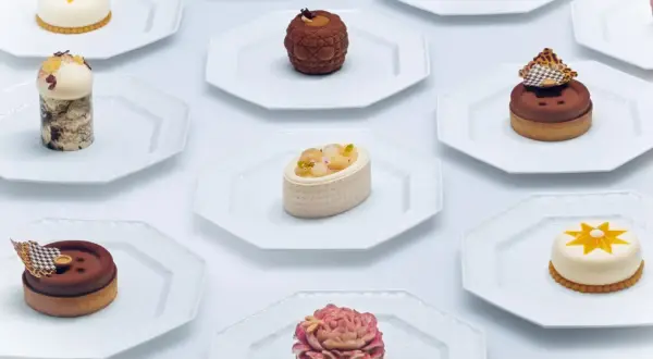 Collection de petits gâteaux raffinés, un véritable produit de luxe alimentaire, présentés sur des assiettes blanches.