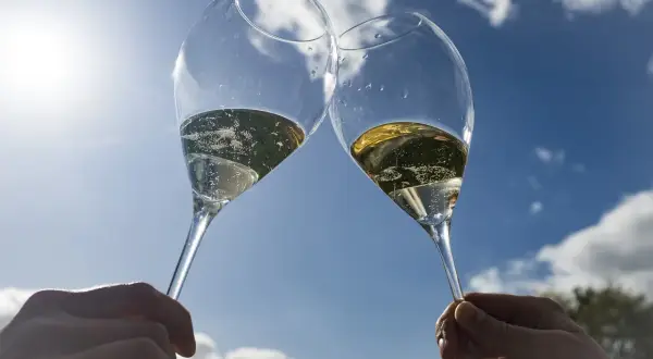 Deux flûtes de champagne pétillant levées en l'air, sous un ciel bleu éclatant. Un toast à Épernay !