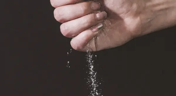 Une main saupoudre du sel, une expression culinaire qui sublime les saveurs.