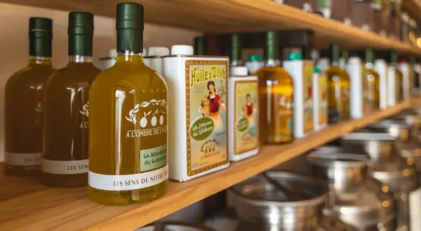 Bouteilles d'huile d'olive "Les Sens de Notre Terre", "A l'ombre de l'Oli" et "La Sélection du Luberon", évoquant les saveurs des terrasses d'Adrien.