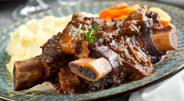 Plat de côte au four, tendre et savoureux, servi avec purée et carottes. Le temps de cuisson est parfait pour cette viande.