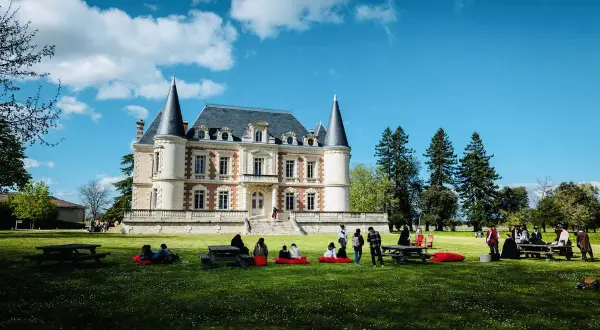 Visite d'un magnifique château dans le Médoc, avec des gens profitant du soleil sur la pelouse.