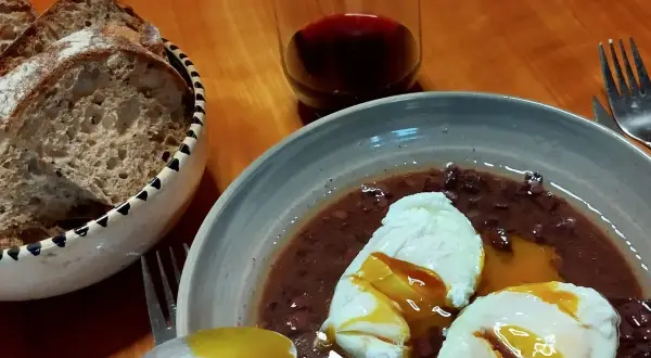 Œufs meurette, un plat d'origine française, servis avec du pain et du vin rouge.