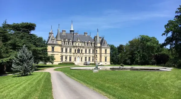 Château majestueux sous un ciel bleu, avec une allée menant à l'entrée. Un lieu idéal pour déguster un champagne Le Gallais.
