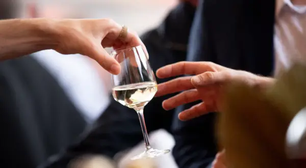 Des mains échangent un verre de vin blanc lors d'une dégustation à Angers.