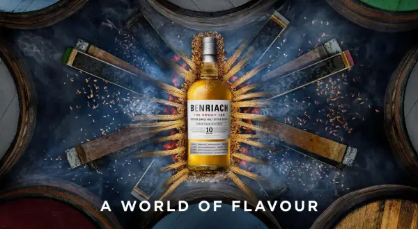 Bouteille de whisky BenRiach The Smoky Ten, entourée de fûts et d'épis de blé, évoquant le savoir-faire de la distillerie.