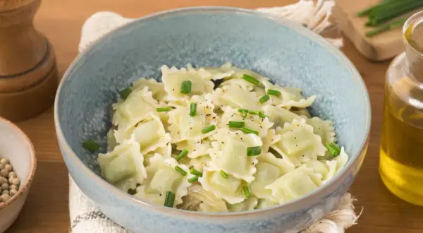 Un plat de ravioli du Dauphiné, généreusement garnis et saupoudrés de ciboulette fraîche et de poivre noir.