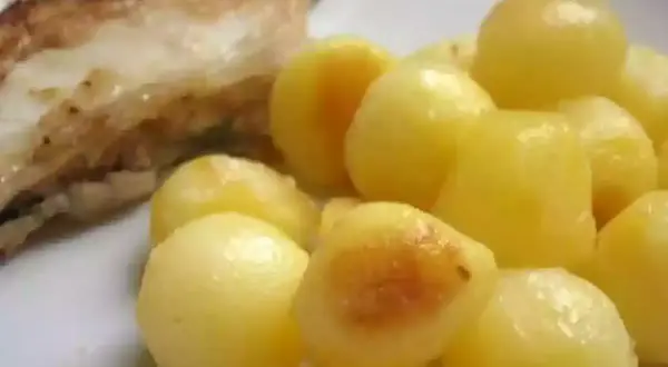 Une assiette de poisson grillé avec une généreuse portion de pomme de terre parisienne, dorée et appétissante.