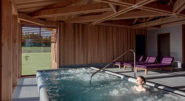 Détente dans un chateau spa à Bordeaux. Une femme profite d'un jacuzzi avec vue sur les vignes.