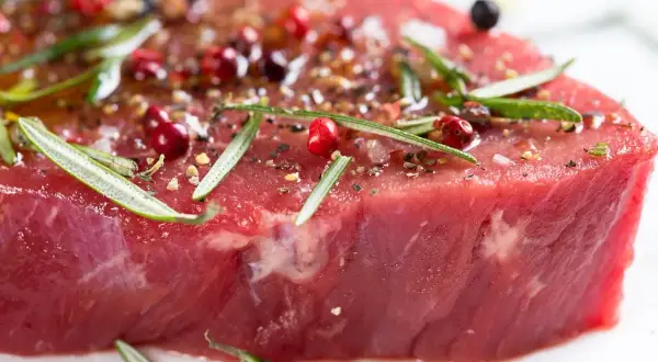 Un morceau de viande rouge, assaisonné de poivre rose, de romarin et d'épices, prêt à devenir l'une des 10 meilleurs viandes du monde.