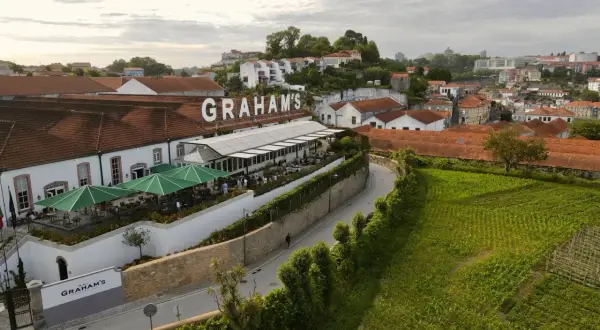 Le vignoble Porto District, avec le nom "GRAHAM'S" en lettres blanches sur le toit, offre une vue sur des bâtiments traditionnels et des champs verdoyants.