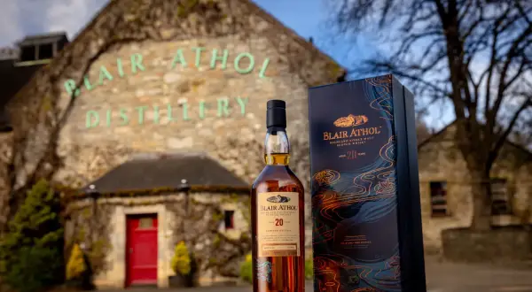 Bouteille de whisky Blair Athol 20 ans et sa boîte devant la distillerie.