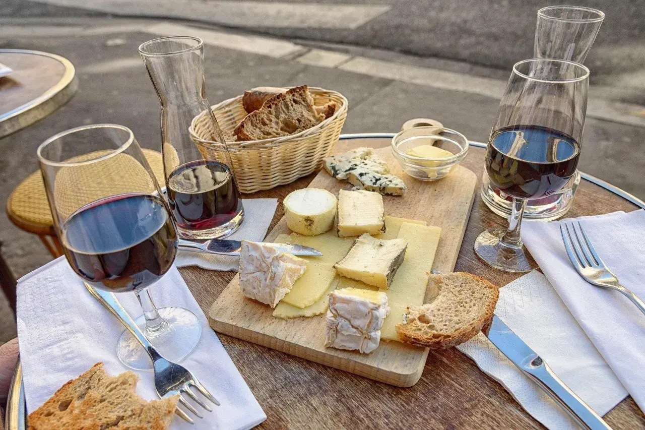 Un plateau de fromages variés, du pain et du vin rouge, une scène qui raconte une belle histoire de la cuisine française.