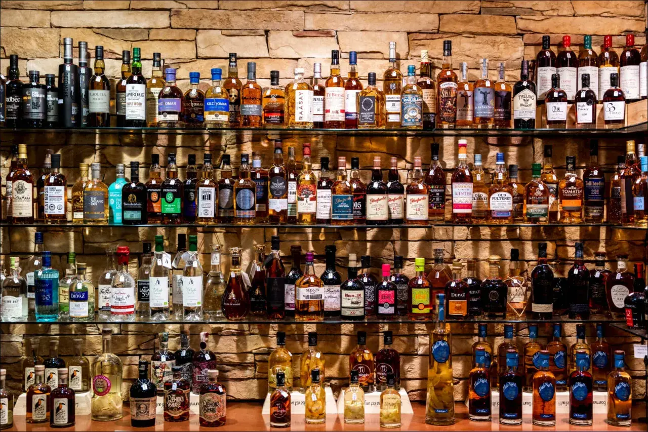 Étagères remplies de bouteilles de whisky et de champagne, un festin pour les amateurs de spiritueux.