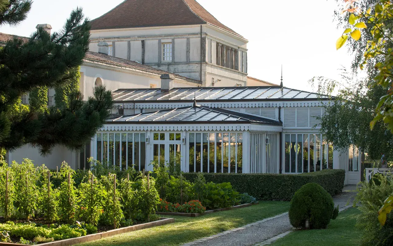 Jardin luxuriant devant une serre élégante, rappelant la beauté du caudalie vignoble.