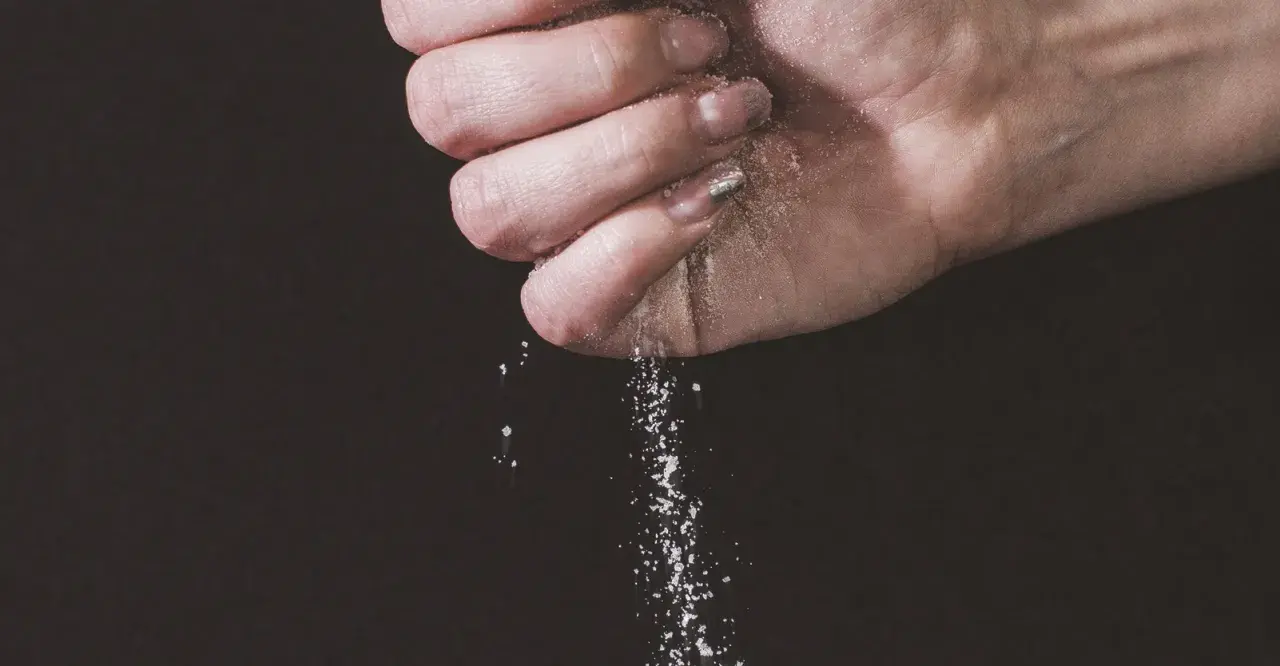 Une main saupoudre du sel, une expression culinaire qui sublime les saveurs.