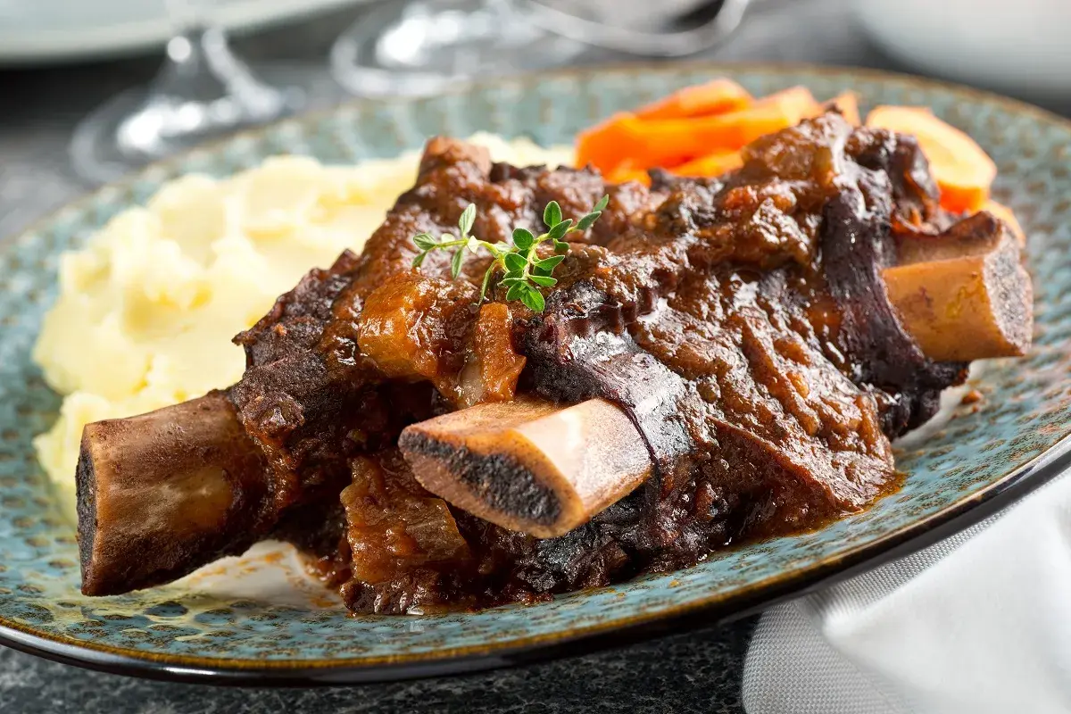 Plat de côte au four, tendre et savoureux, servi avec purée et carottes. Le temps de cuisson est parfait pour cette viande.