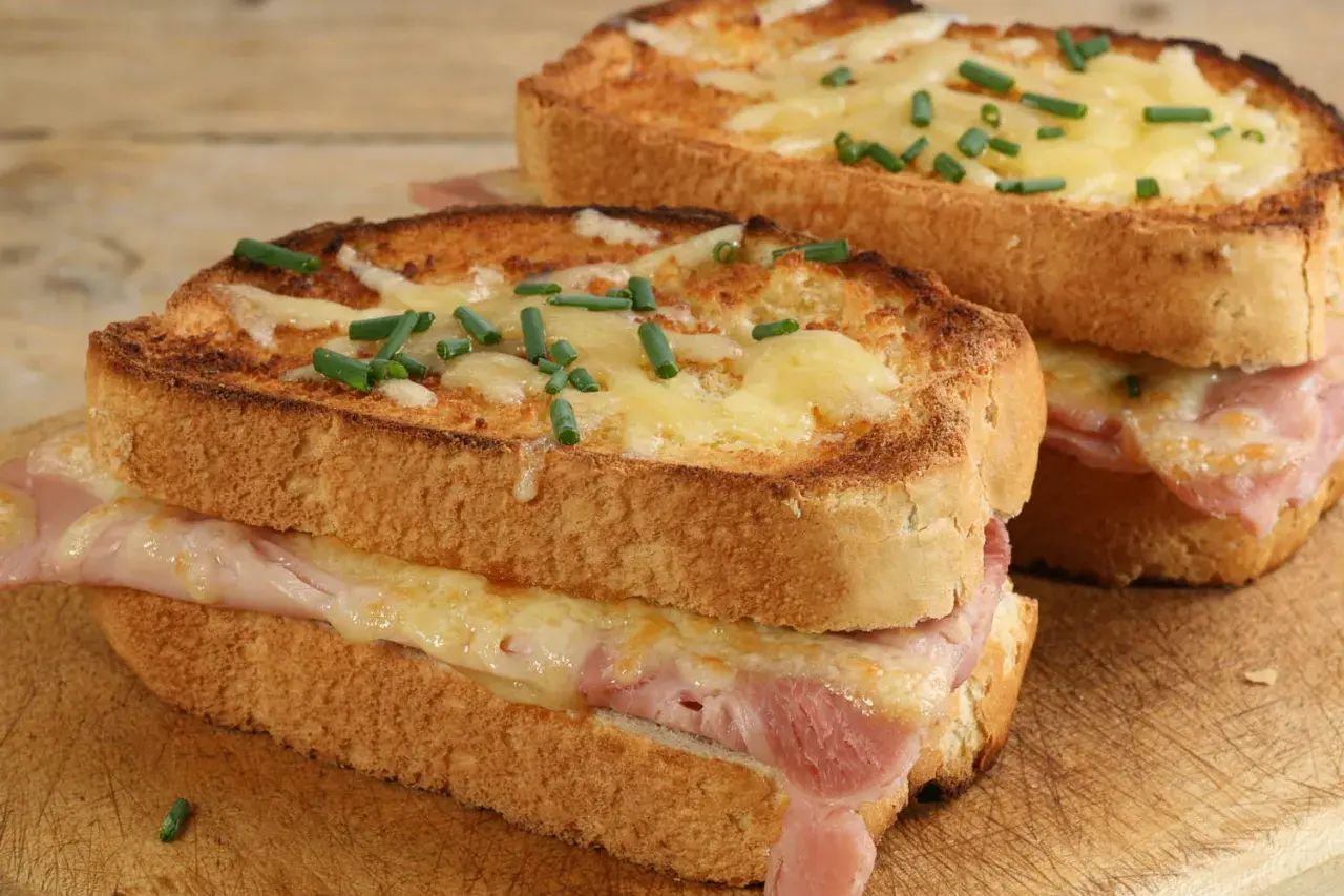 Deux croque monsieur bistrot, dorés et gratinés, garnis de jambon et fromage fondant, parsemés de ciboulette fraîche.