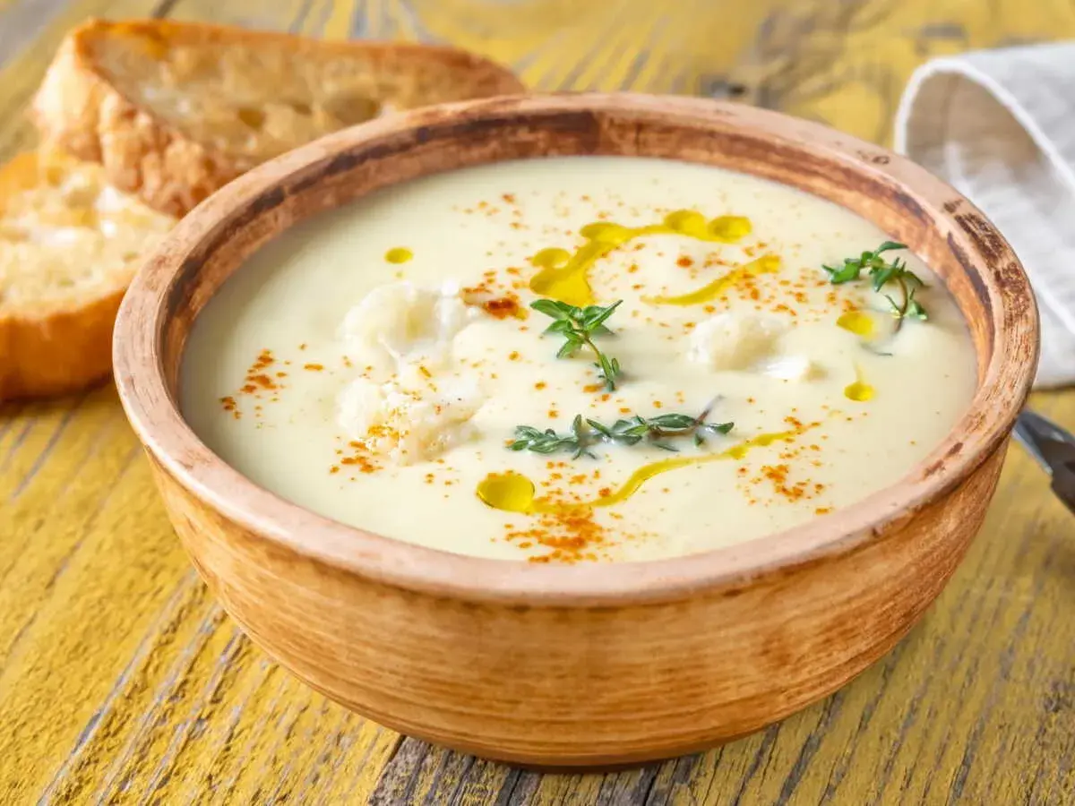 Un onctueux potage Dubarry, garni de chou-fleur, d'huile d'olive et de thym, servi avec des toasts grillés.