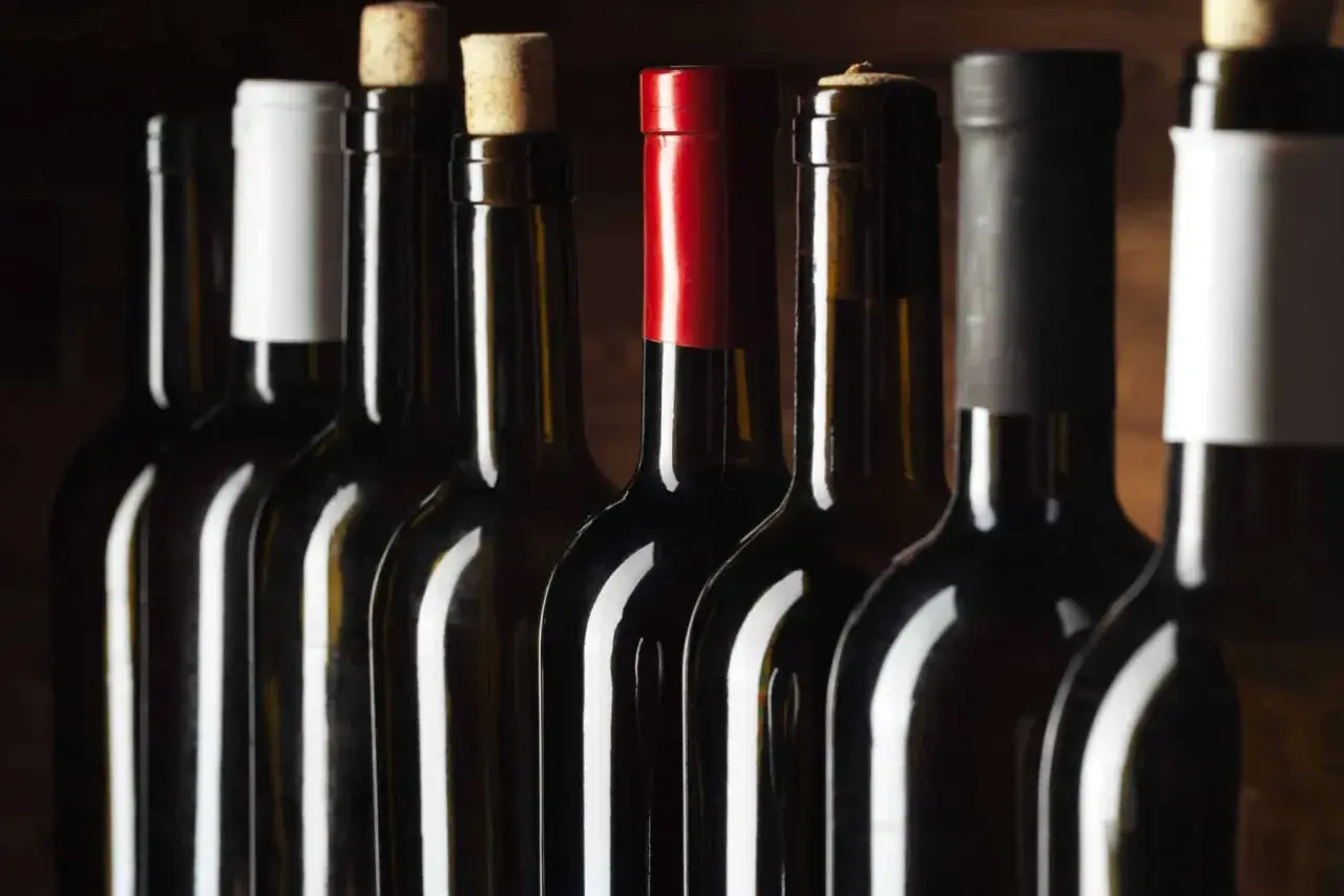 Bouteilles de vin alignées, certaines avec bouchons en liège, d'autres avec capsules. Un aperçu des trésors d'un domaine viticole Roussillon.