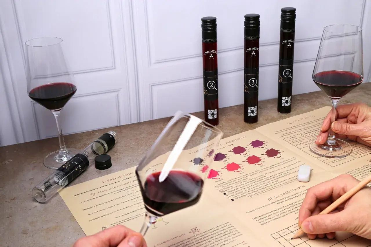 Dégustation vin Touraine : verres de vin rouge, fioles numérotées et guide d'analyse pour une expérience œnologique.