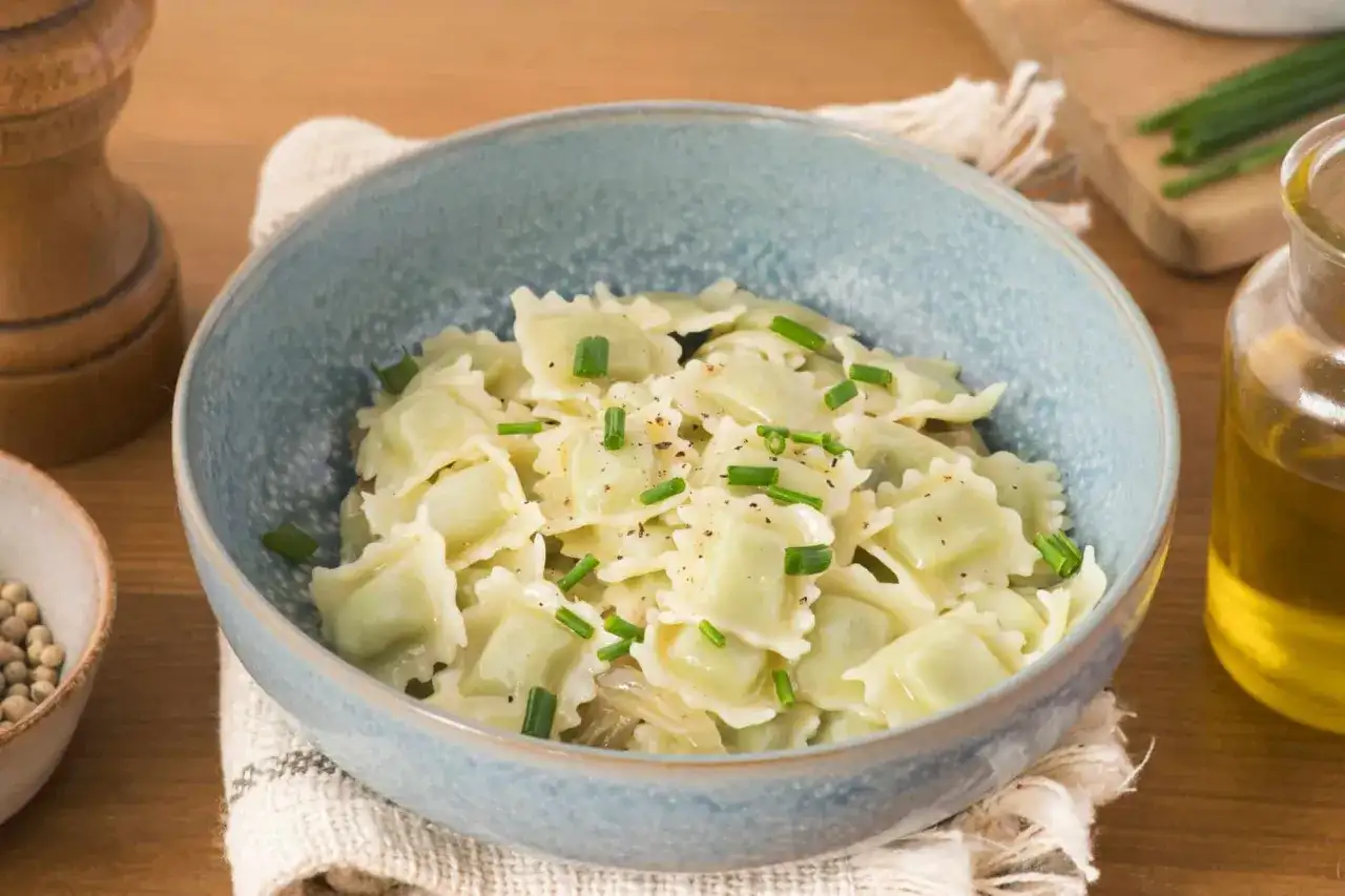 Un plat de ravioli du Dauphiné, généreusement garnis et saupoudrés de ciboulette fraîche et de poivre noir.