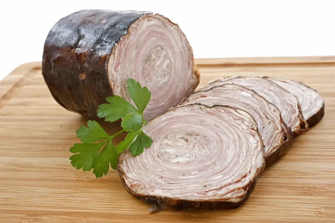 Andouillette tranch&eacute;e sur planche en bois, avec persil. Une image pour comprendre la diff&eacute;rence entre andouille et andouillette.