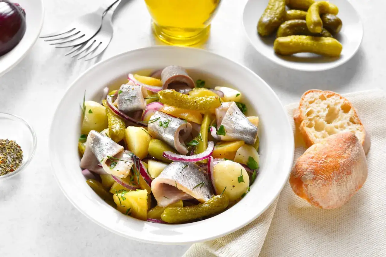 Salade de harengs &agrave; l'huile avec pommes de terre, oignons rouges et cornichons. Une recette simple et savoureuse.