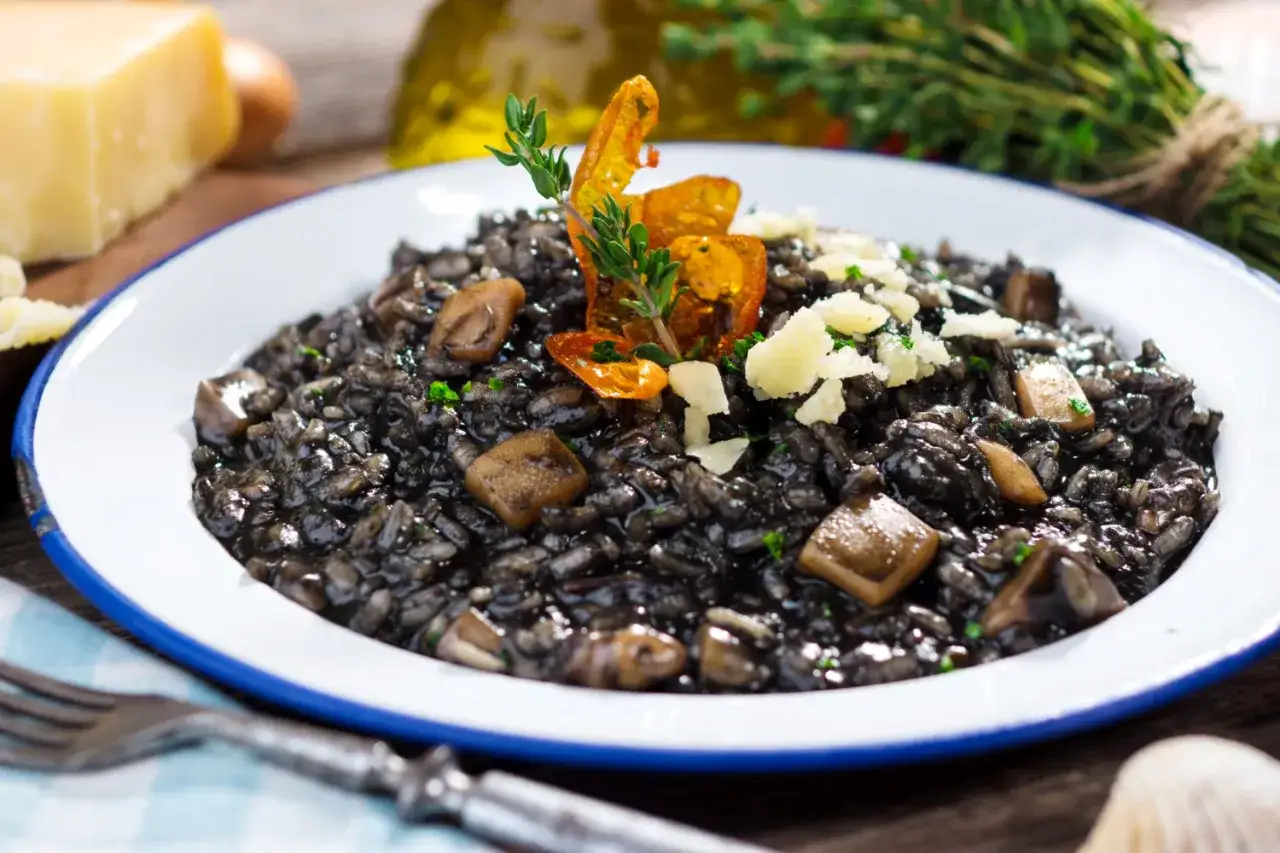 Risotto noir, &agrave; base d'encre de seiche c'est quoi ? Ce plat savoureux est garni de champignons et de copeaux de parmesan.