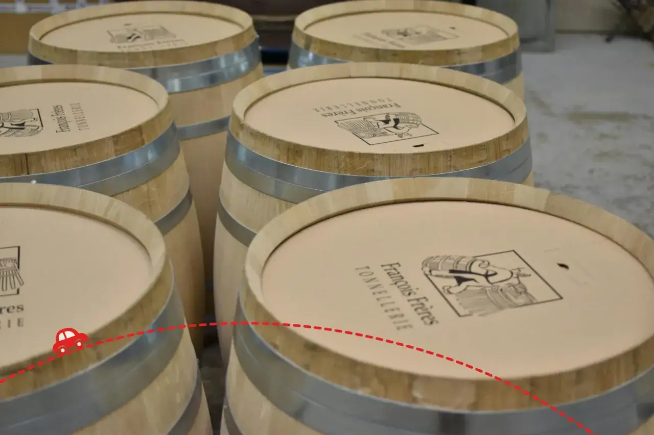 Visite tonnellerie Bourgogne : des fûts en bois neufs, prêts pour le vin. Une petite voiture rouge suit un chemin pointillé sur les couvercles.