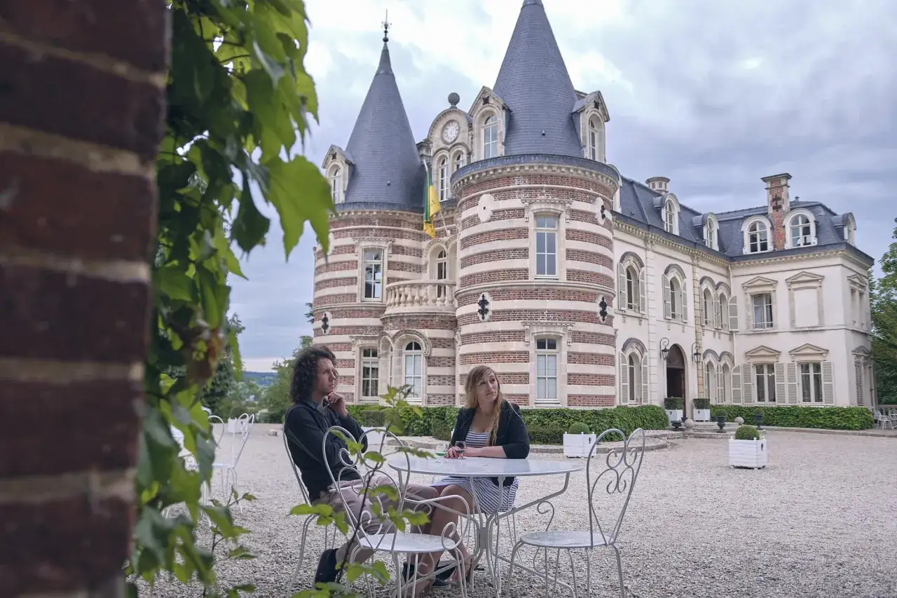 Un couple profite d'un moment de détente devant un château, peut-être en dégustant un champagne à Épernay.