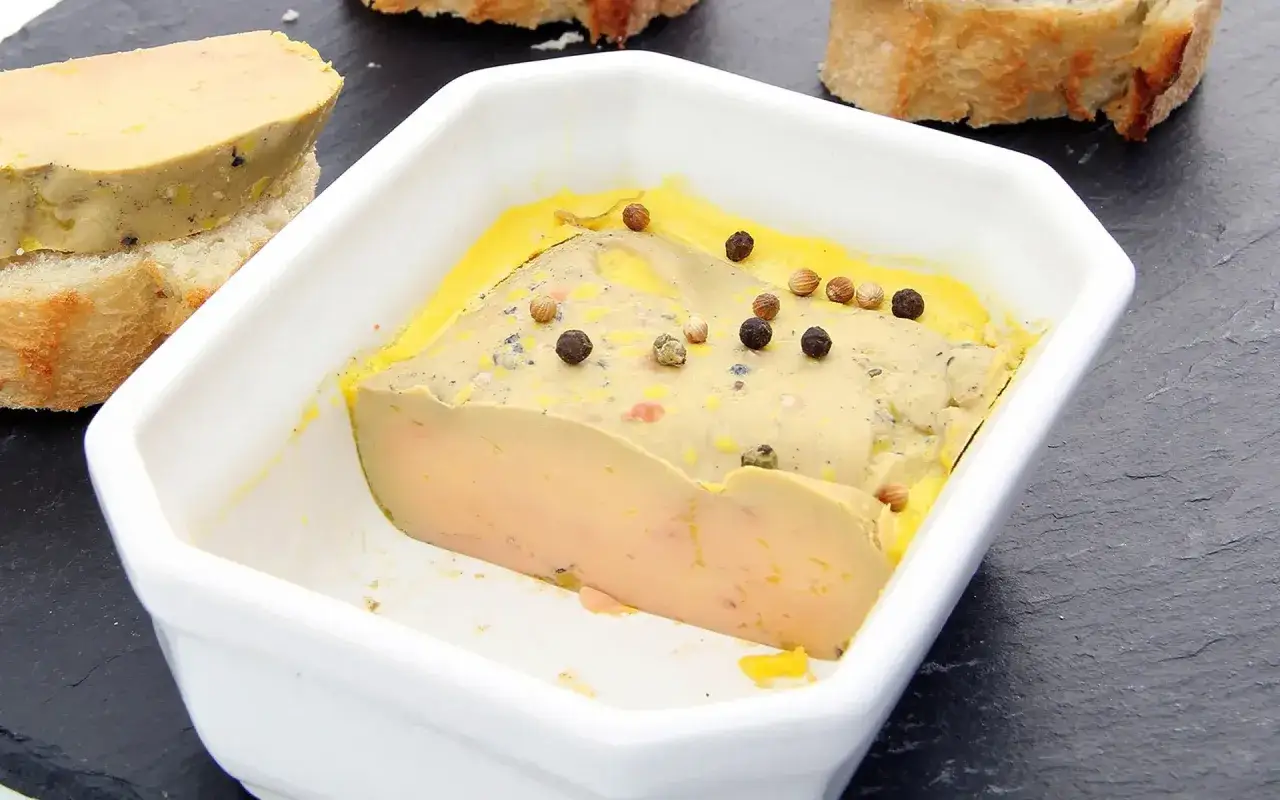 Un délice de foie gras mi cuit ou entier, parsemé de grains de poivre, prêt à être dégusté sur des toasts croustillants.