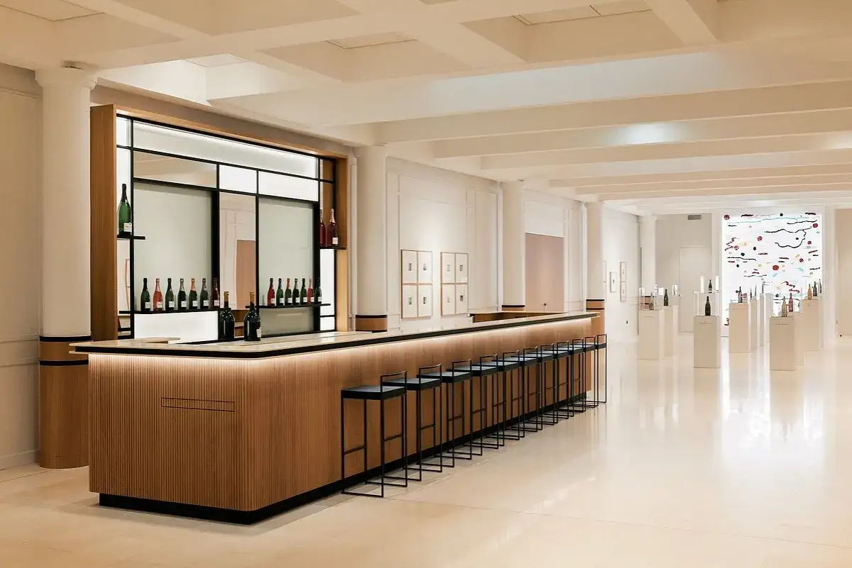 Bar moderne et élégant à la maison Taittinger Reims, avec des bouteilles de champagne exposées.