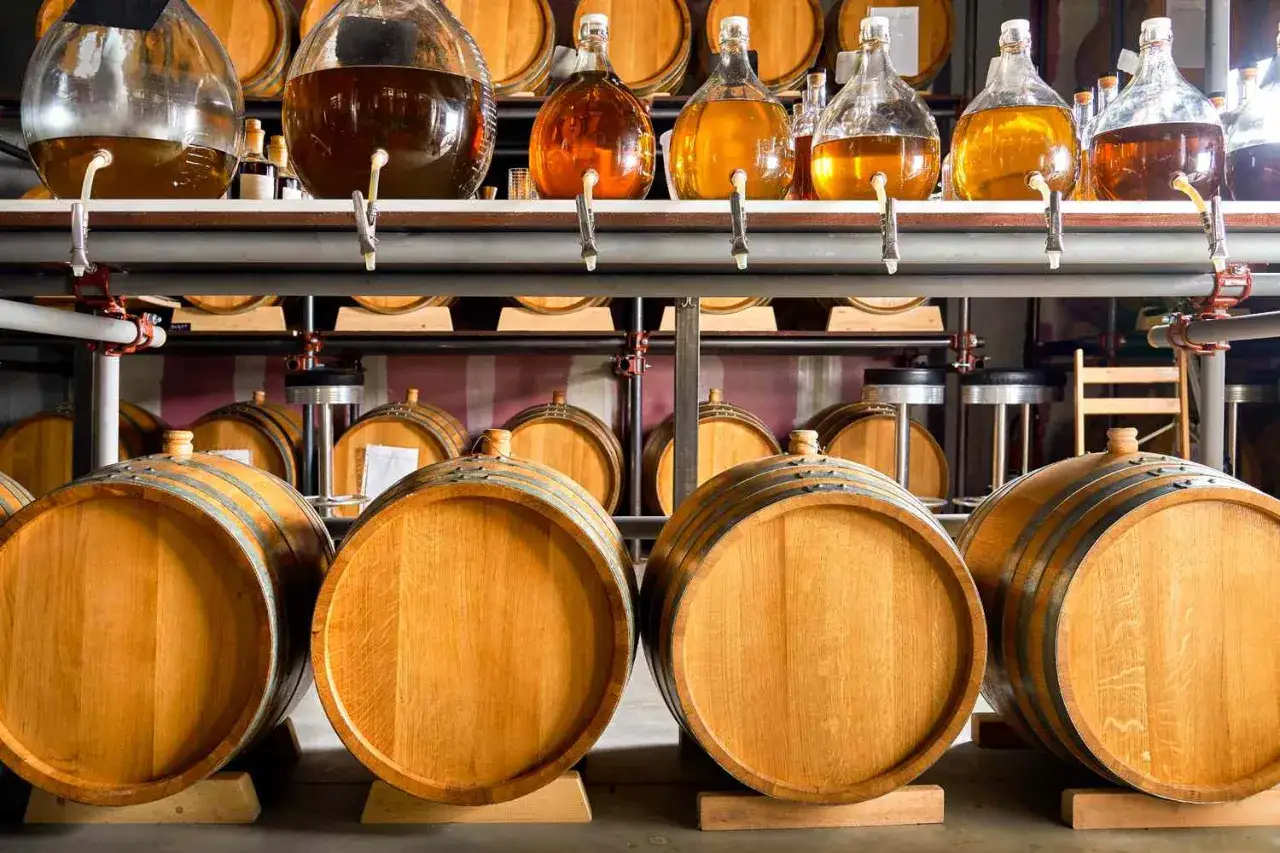 Cuves et fûts en bois dans une distillerie, prêts pour la création de whisky.