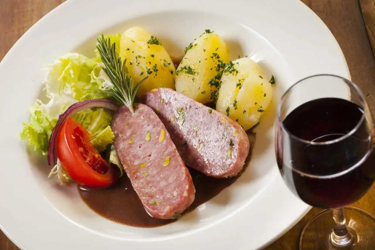 Saucisson lyonnais, pommes de terre et salade, un classique de la gastronomie lyonnaise, accompagn&eacute; d'un verre de vin rouge.