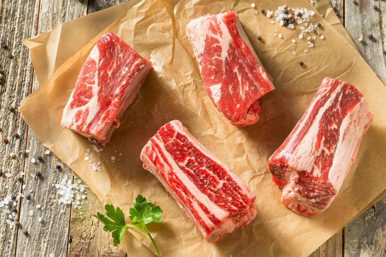 Quatre morceaux de plat de c&ocirc;te cru, pr&ecirc;ts pour le temps de cuisson au four. Sel et poivre pars&egrave;ment le papier cuisson.
