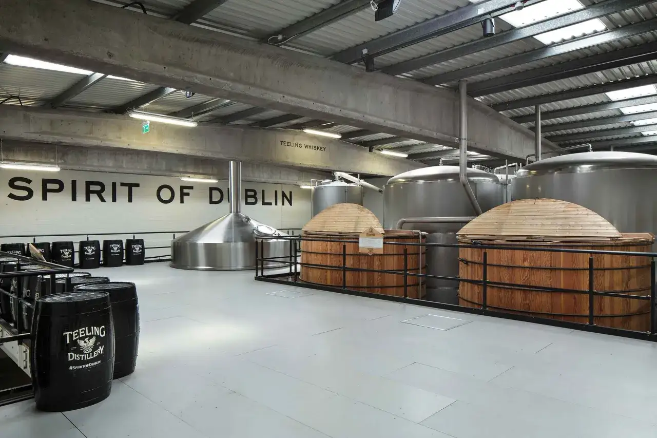 Intérieur d'une distillerie de whisky à Dublin, avec des cuves en bois, des alambics et des tonneaux marqués Teeling Distillery.