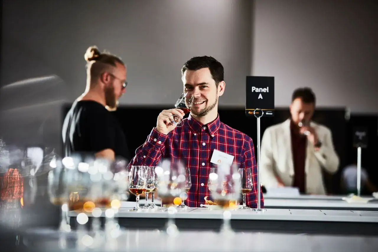 Un homme déguste un whisky lors d'une dégustation, peut-être pour les World Whisky Awards.