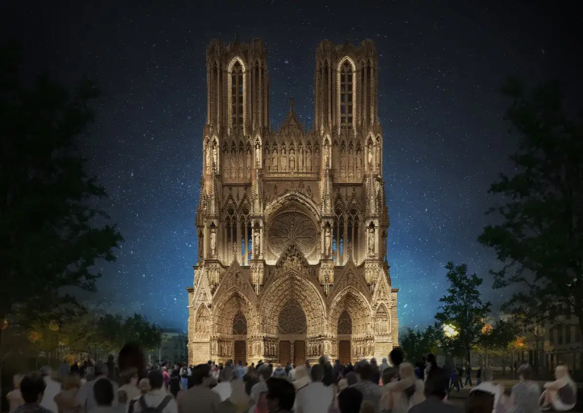 La cathédrale de Reims illuminée la nuit, sous un ciel étoilé. Une foule admire ce spectacle, une idée de que faire à Reims.