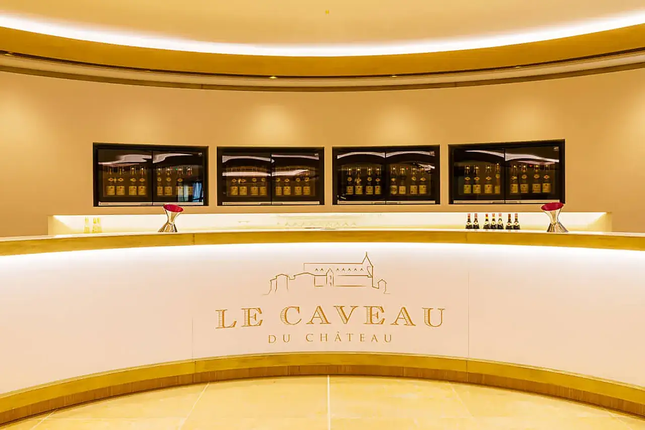 Le caveau Guigal, un comptoir moderne avec des bouteilles de vin exposées dans des vitrines lumineuses et une enseigne dorée.